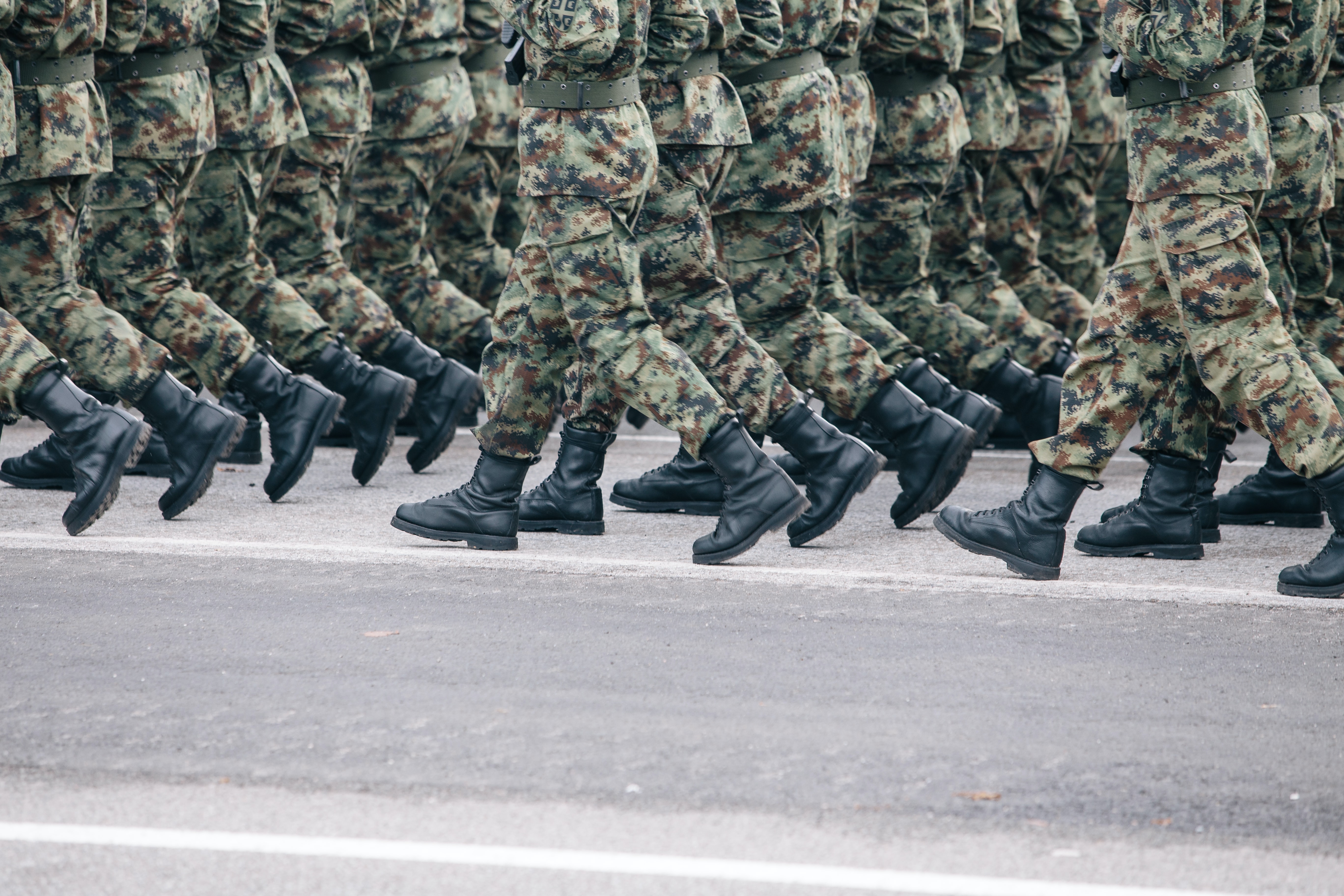 Soldiers dressed in army camouflage march in formation.